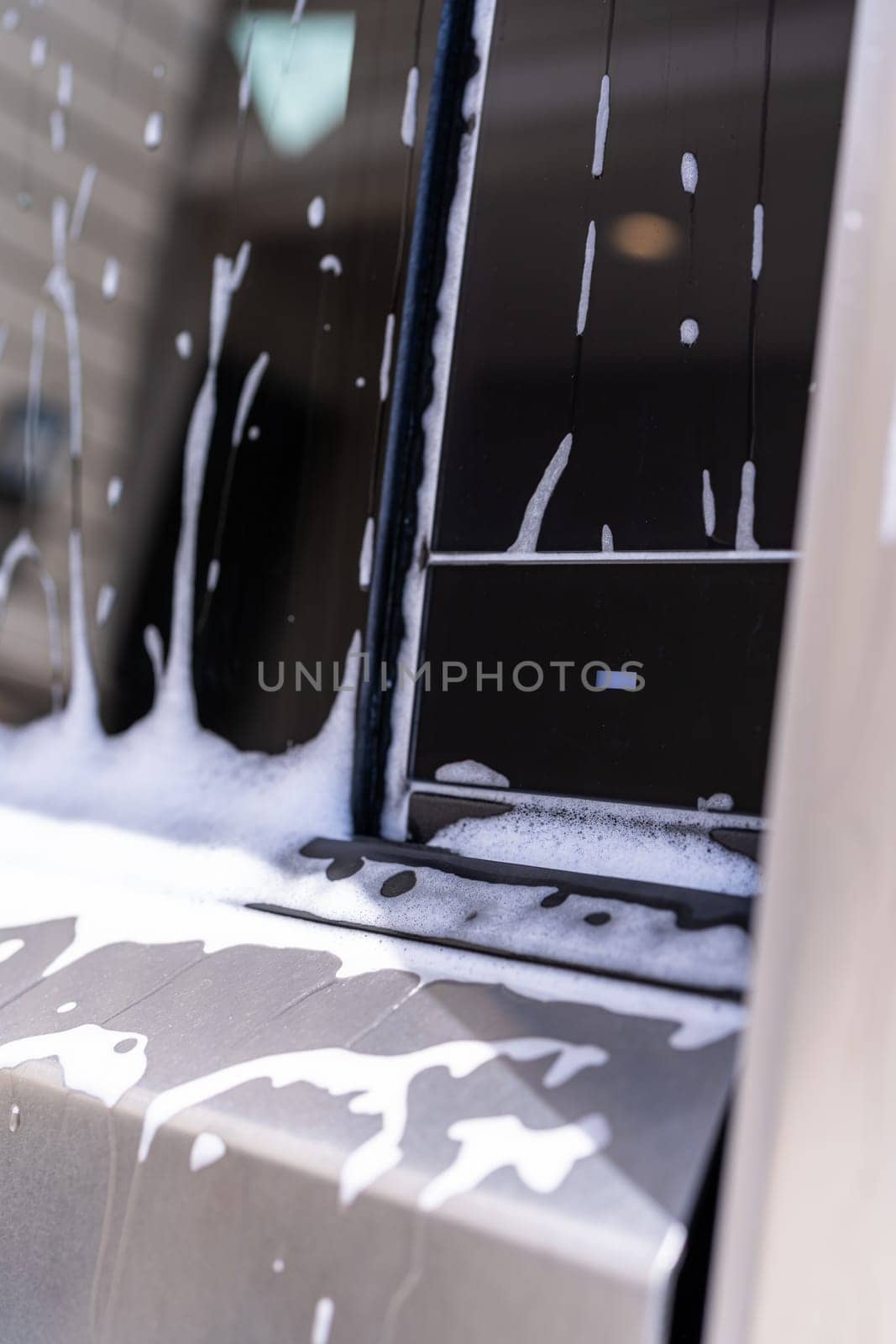 Denver, Colorado, USA-May 5, 2024-A close-up view of a Tesla Cybertruck covered in soap suds during a car wash, showcasing the flowing patterns over its angular surface and highlighting the unique design of the vehicle body.