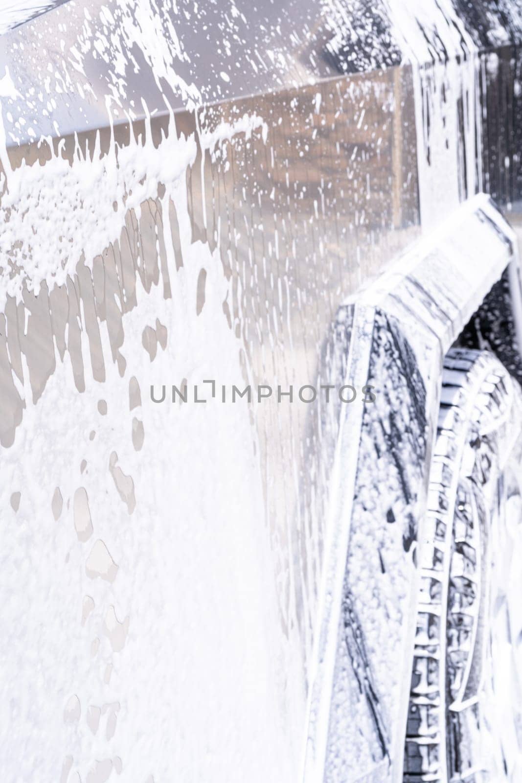 Denver, Colorado, USA-May 5, 2024-This image captures soapy water streaming beautifully down the metallic, angular side of a Tesla Cybertruck during a wash. The close-up showcases the sleek lines and unique design of the vehicle.