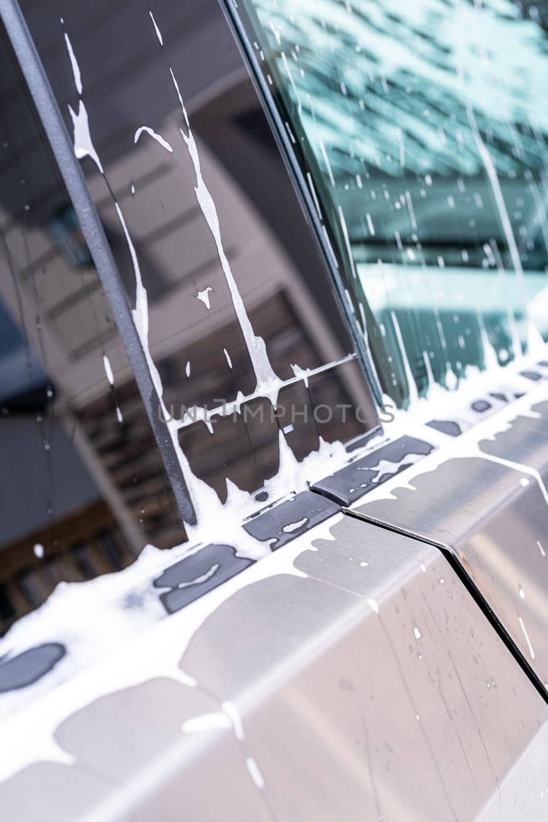 Denver, Colorado, USA-May 5, 2024-A close-up view of a Tesla Cybertruck covered in soap suds during a car wash, showcasing the flowing patterns over its angular surface and highlighting the unique design of the vehicle body.