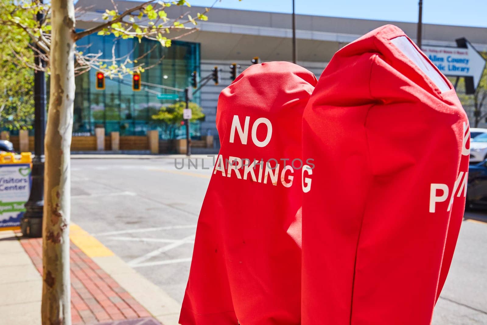 Vivid red NO PARKING meters in downtown Fort Wayne, set against a modern public building.