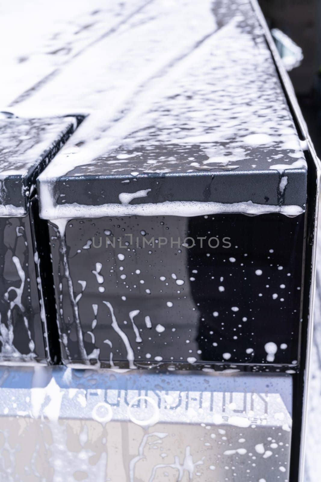 Denver, Colorado, USA-May 5, 2024-This image captures a detailed view of soap suds accumulating and dripping off the edge of a Tesla Cybertruck window during a wash, highlighting the vehicle distinct, clean lines and reflective surfaces.