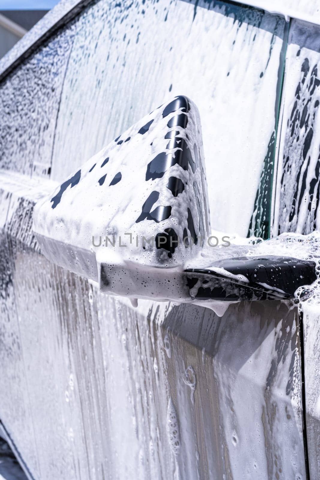 Denver, Colorado, USA-May 5, 2024-This image captures a close-up view of the Tesla Cybertruck side mirror covered in soap suds during a car wash, emphasizing the vehicle unique angular design and rugged exterior.