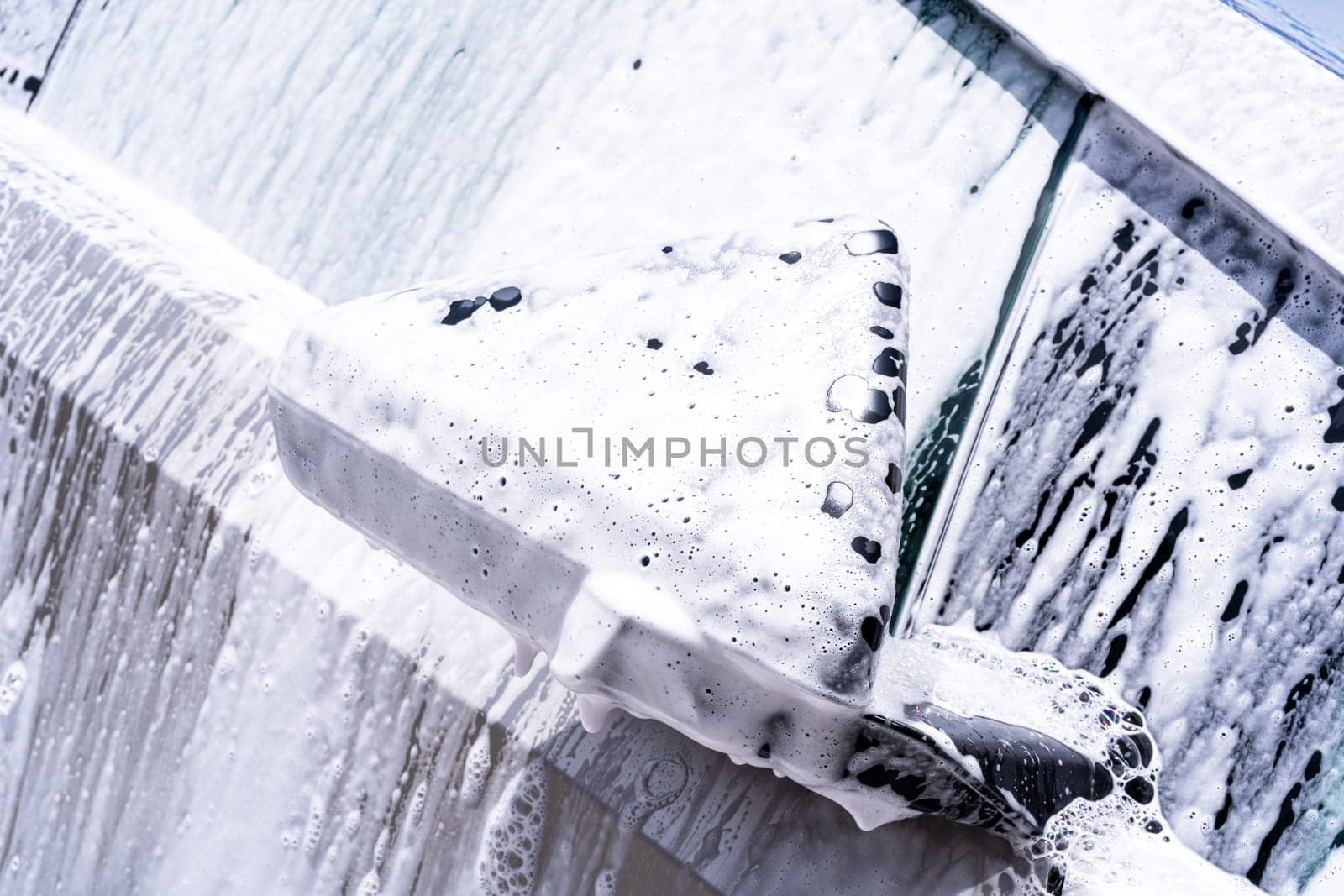 Denver, Colorado, USA-May 5, 2024-This image captures a close-up view of the Tesla Cybertruck side mirror covered in soap suds during a car wash, emphasizing the vehicle unique angular design and rugged exterior.