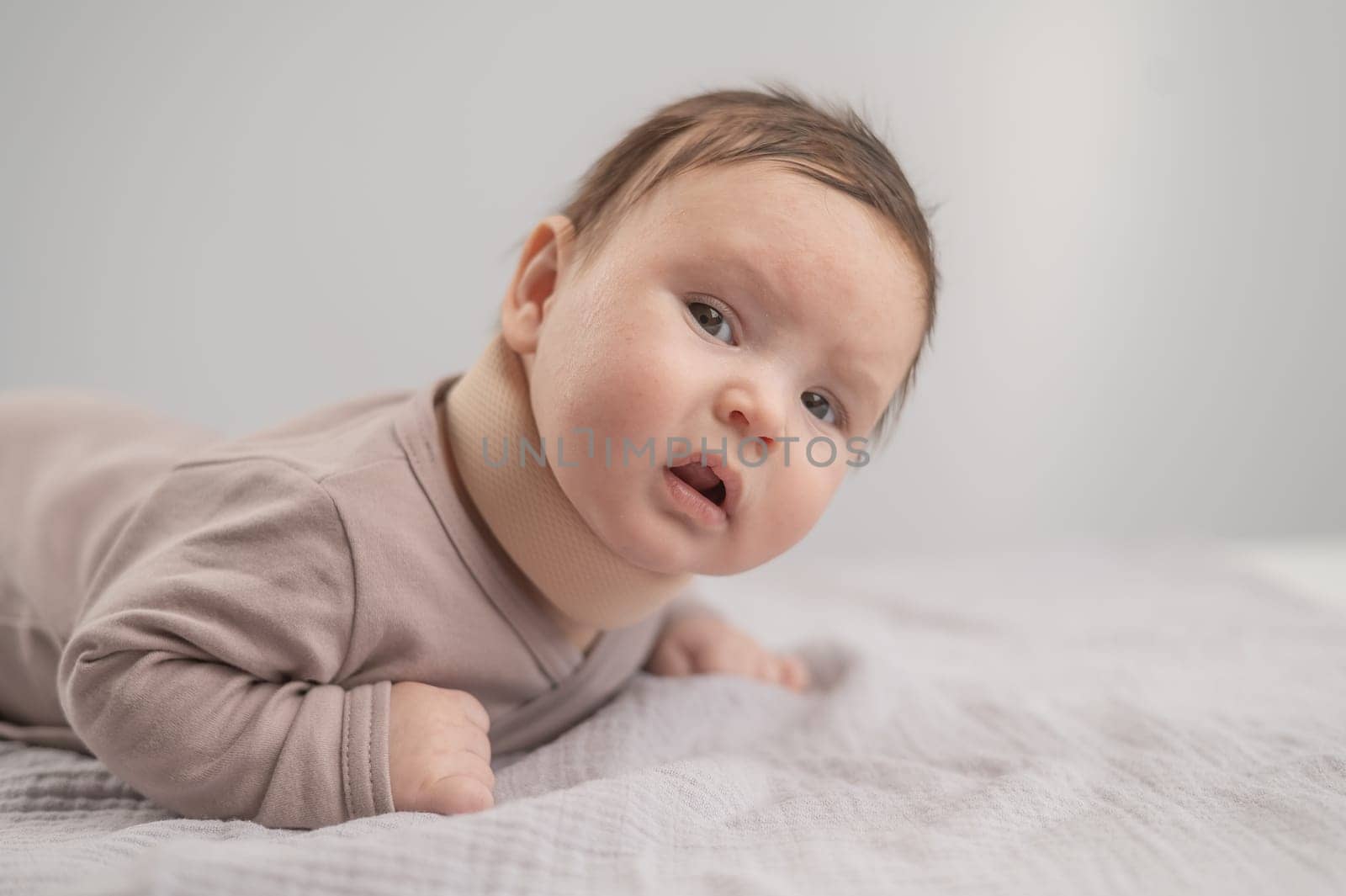Portrait of a newborn baby lying on his stomach in an orthopedic collar