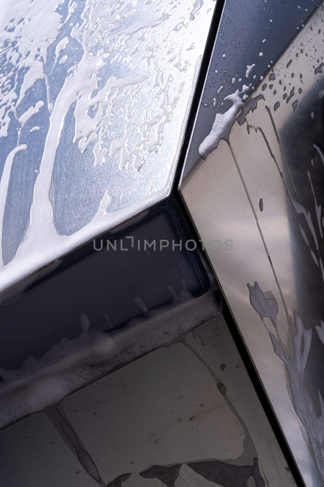 Denver, Colorado, USA-May 5, 2024-This image features a close-up view of the Tesla Cybertruck wheel and angular body design covered in soap and water during a thorough car wash, highlighting the unique textures and robust details of the electric truck.