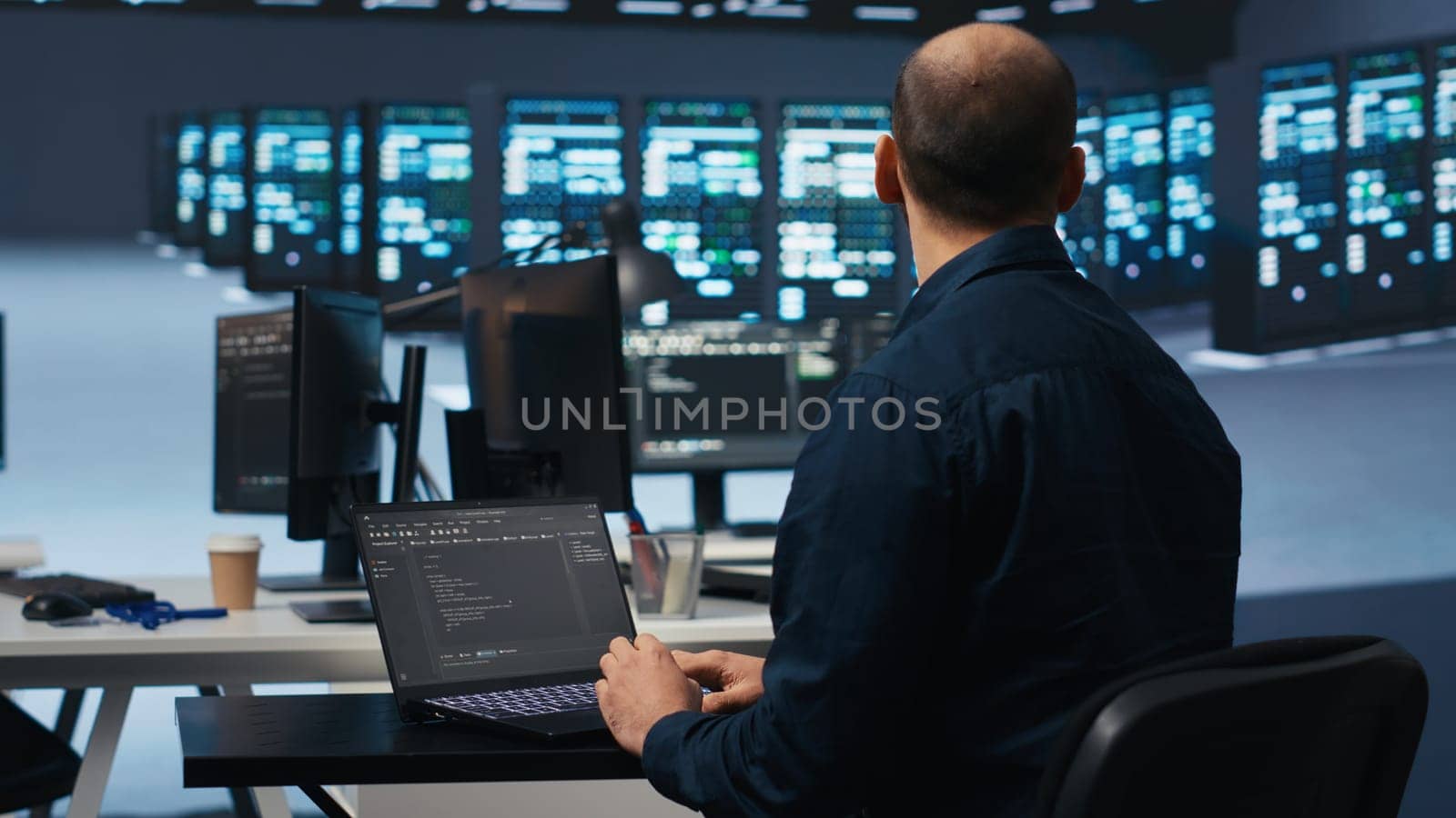 Computer scientist using laptop device to do programming in data center room housing servers . IT supervisor writing code on notebook to mend data storage facility racks doing computational operations