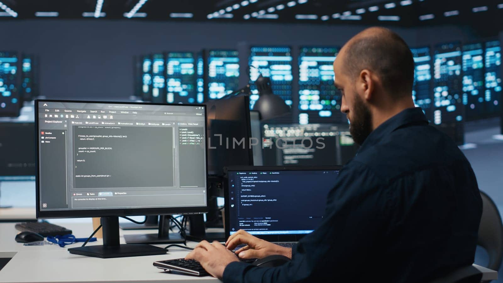 Developer typing code, working in network security data center facility, ensuring optimal performance. IT professional using desktop PC to monitor energy consumption across blade server clusters