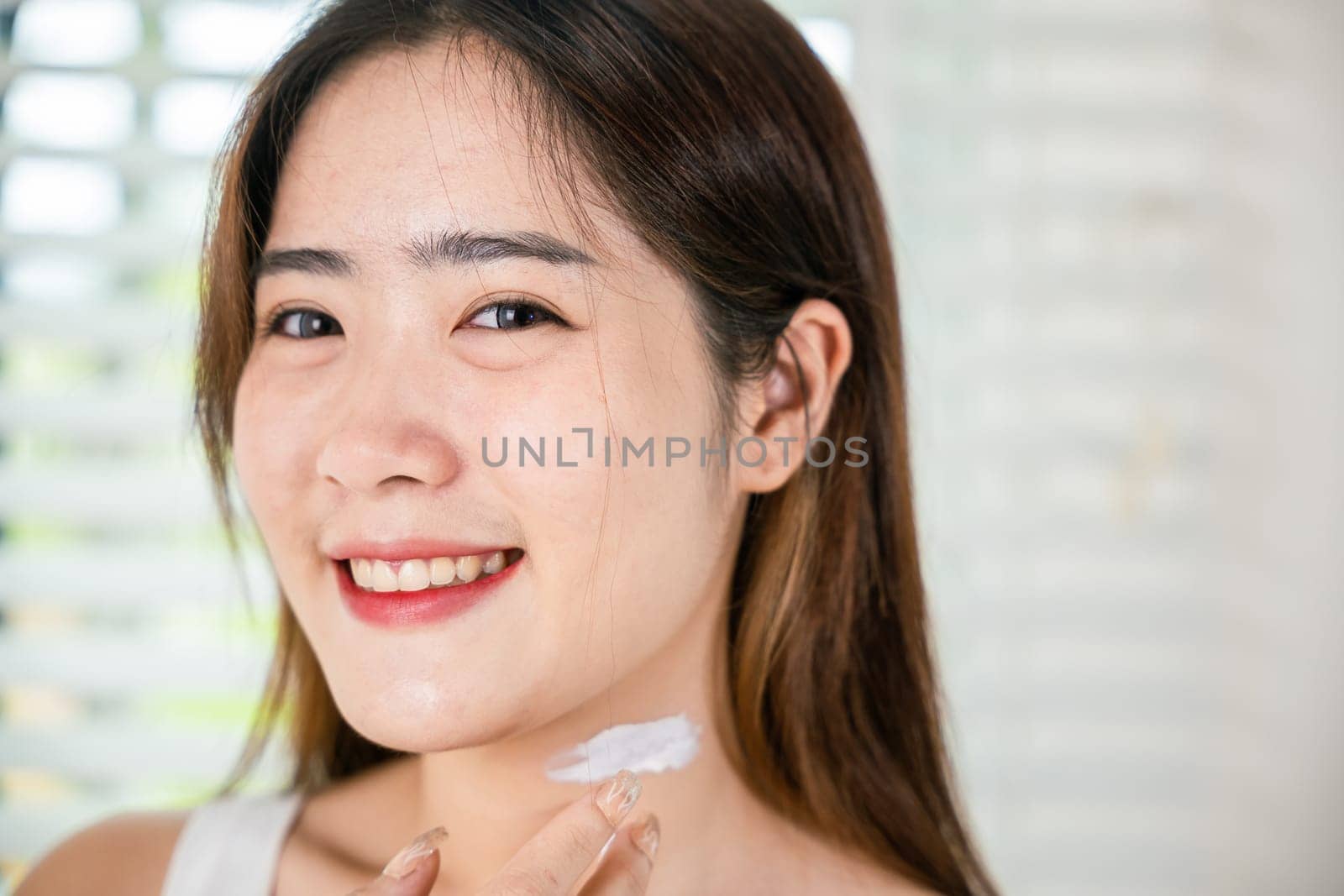 Happy woman smiling apply lotion moisturizer on her neck after shower, Asian beautiful young female applying cosmetic cream on neck at home, Beauty skin care cosmetic protect and nourish skin concept
