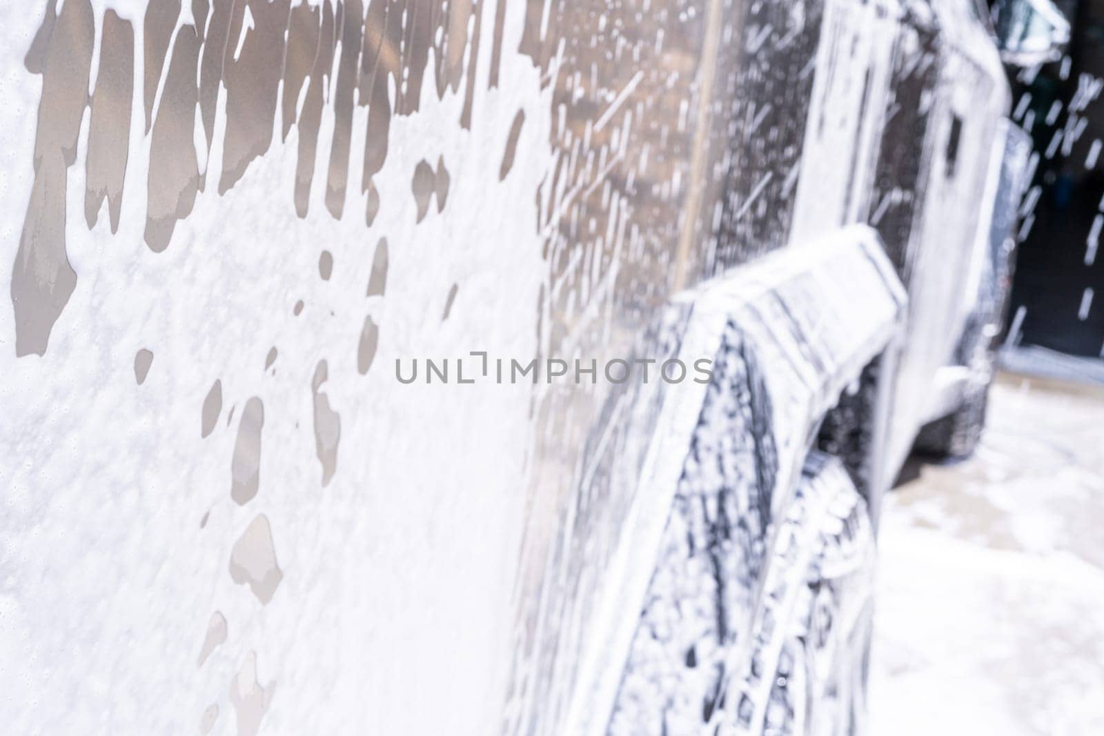 Denver, Colorado, USA-May 5, 2024-This image captures soapy water streaming beautifully down the metallic, angular side of a Tesla Cybertruck during a wash. The close-up showcases the sleek lines and unique design of the vehicle.