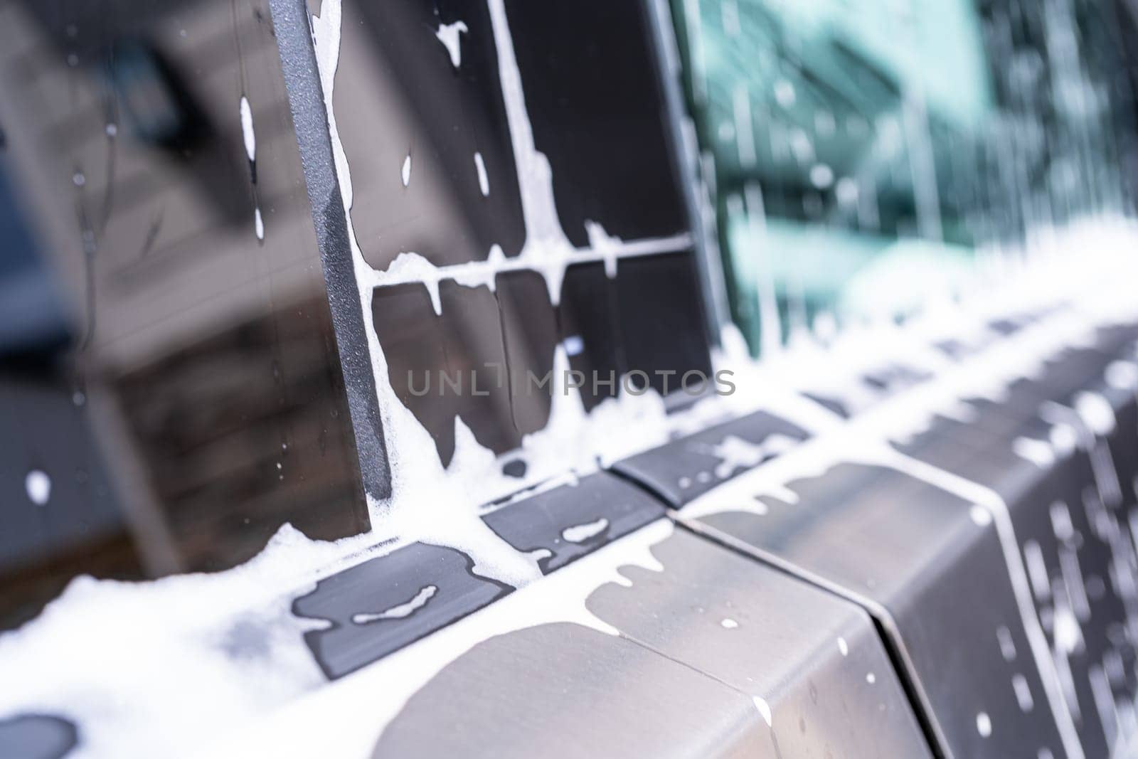 Denver, Colorado, USA-May 5, 2024-This image captures soapy water streaming beautifully down the metallic, angular side of a Tesla Cybertruck during a wash. The close-up showcases the sleek lines and unique design of the vehicle.