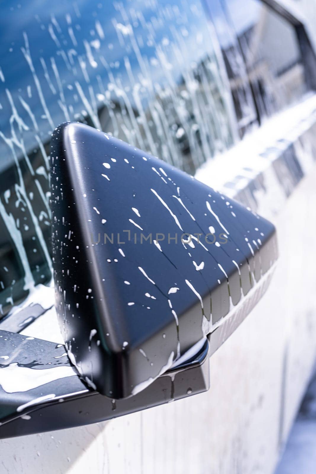 Denver, Colorado, USA-May 5, 2024-This image captures a close-up view of the Tesla Cybertruck side mirror covered in soap suds during a car wash, highlighting the vehicle distinctive angular design and rugged exterior.