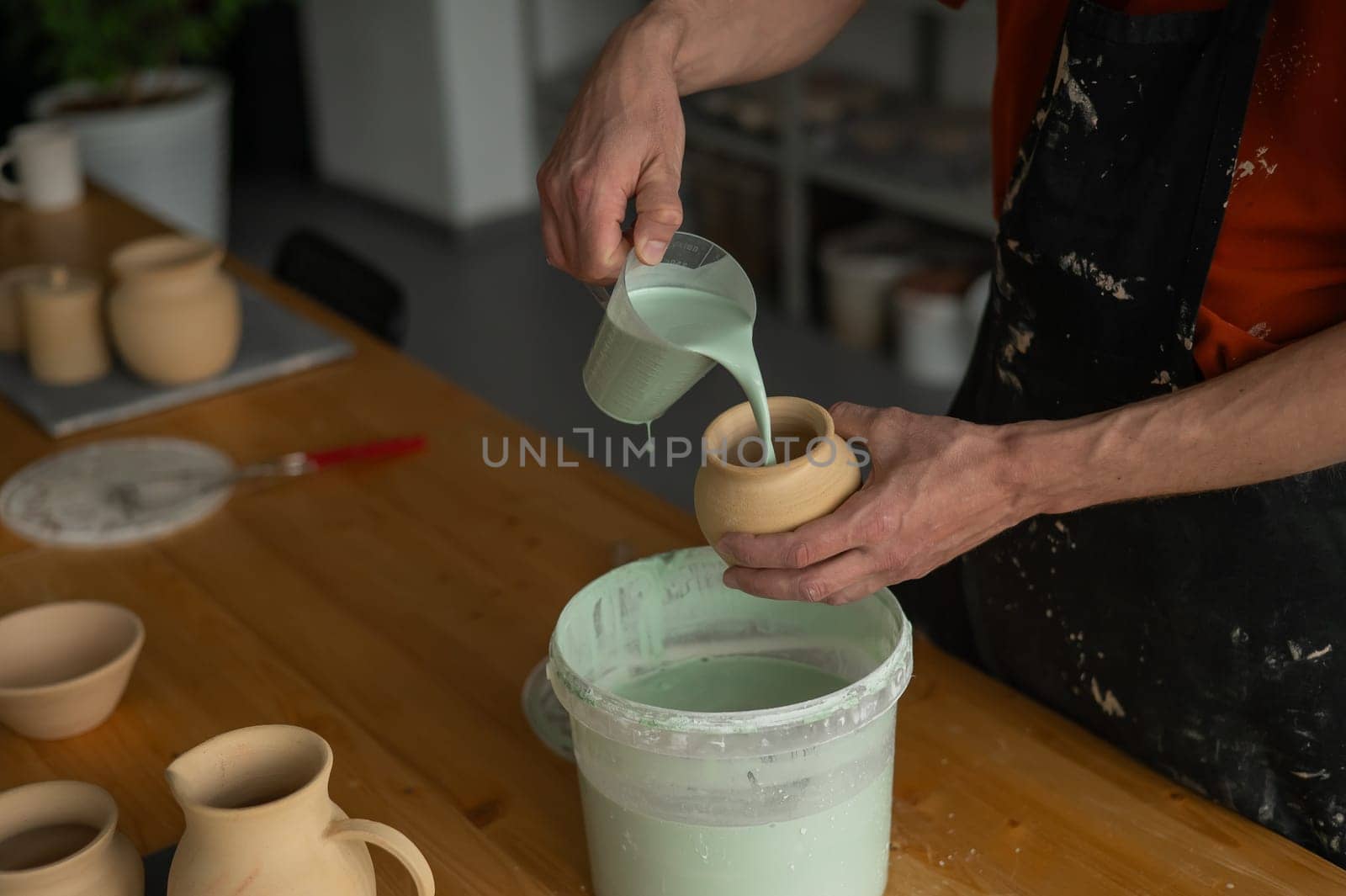 Close-up of a potter's hands glazing a pottery piece. by mrwed54