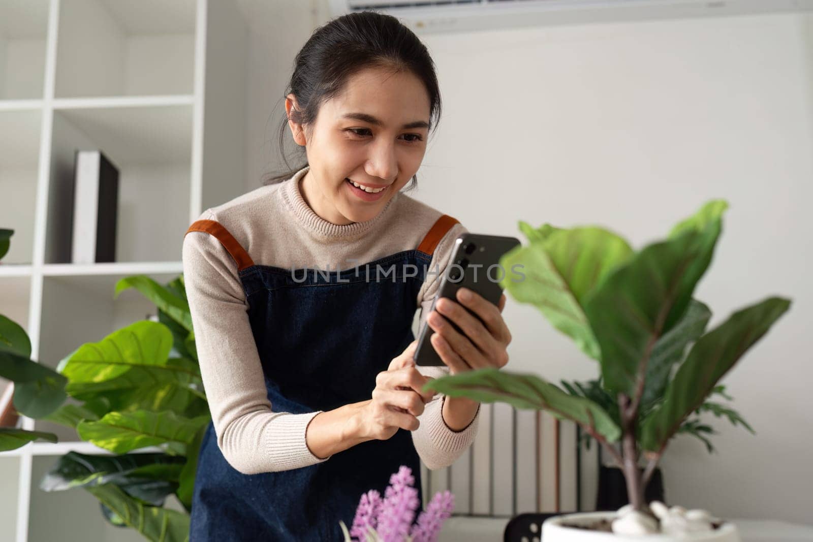 woman hold mobile and take picture of newly plant tree. eco friendly home.