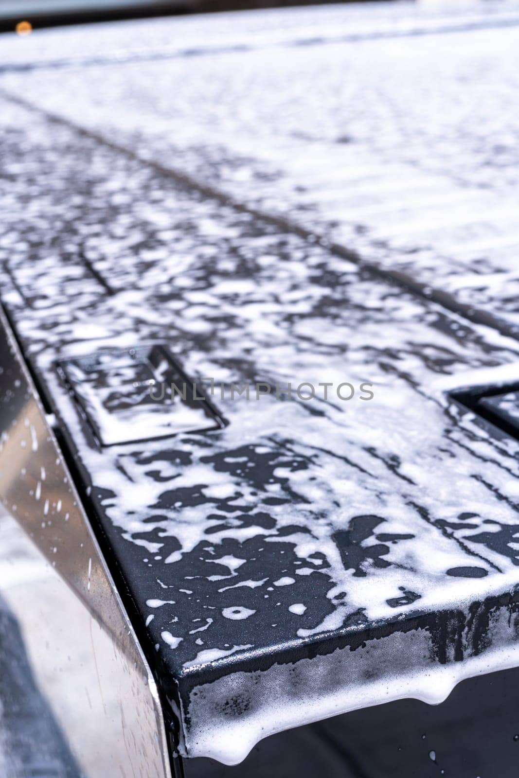 Denver, Colorado, USA-May 5, 2024-This image captures a detailed view of soap suds accumulating and dripping off the edge of a Tesla Cybertruck window during a wash, highlighting the vehicle distinct, clean lines and reflective surfaces.