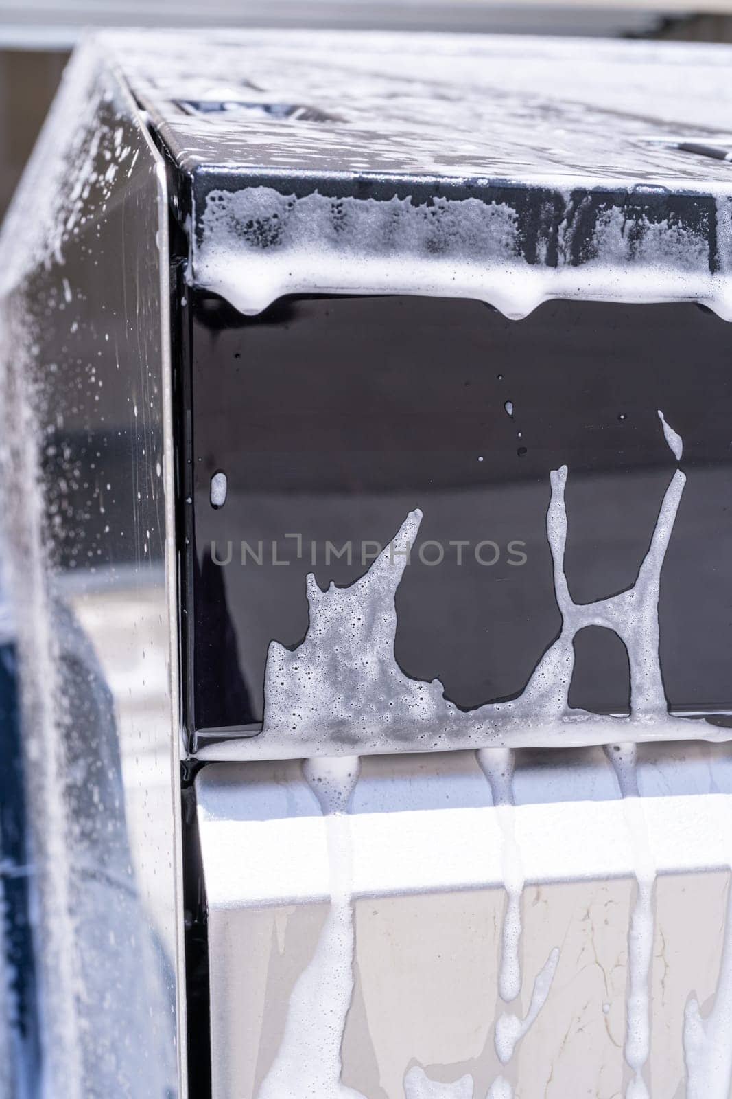 Denver, Colorado, USA-May 5, 2024-This image captures a detailed view of soap suds accumulating and dripping off the edge of a Tesla Cybertruck window during a wash, highlighting the vehicle distinct, clean lines and reflective surfaces.