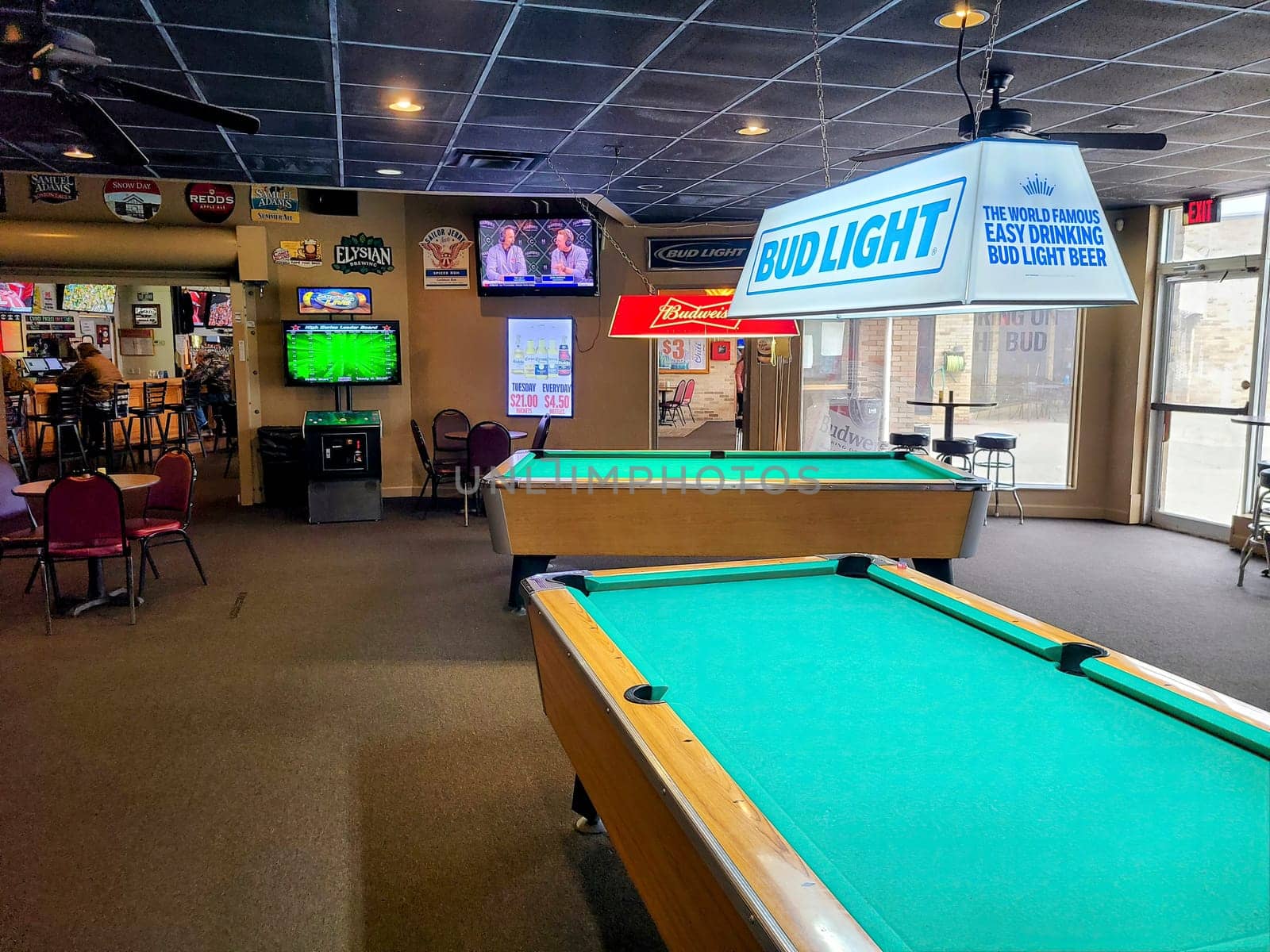 Casual sports bar in Fort Wayne with pool table, vibrant signage, and TVs broadcasting live sports.