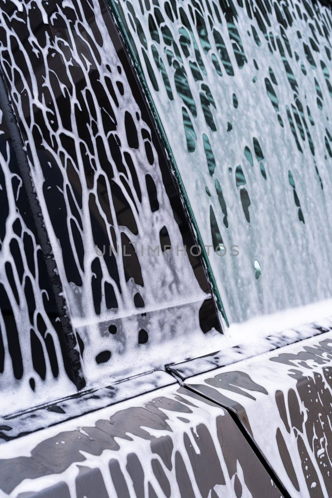 Denver, Colorado, USA-May 5, 2024-A close-up view of a Tesla Cybertruck covered in soap suds during a car wash, showcasing the flowing patterns over its angular surface and highlighting the unique design of the vehicle body.