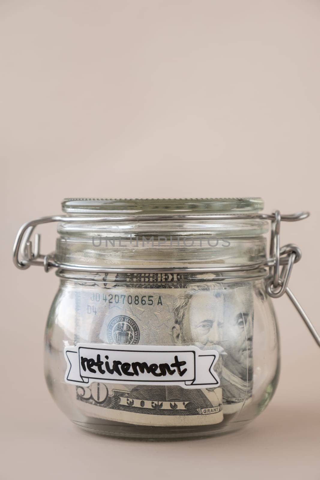 Glass jar full of American currency dollars cash banknote with text RETIREMENT. Preparation saving money. Moderate consumption and economy by anna_stasiia