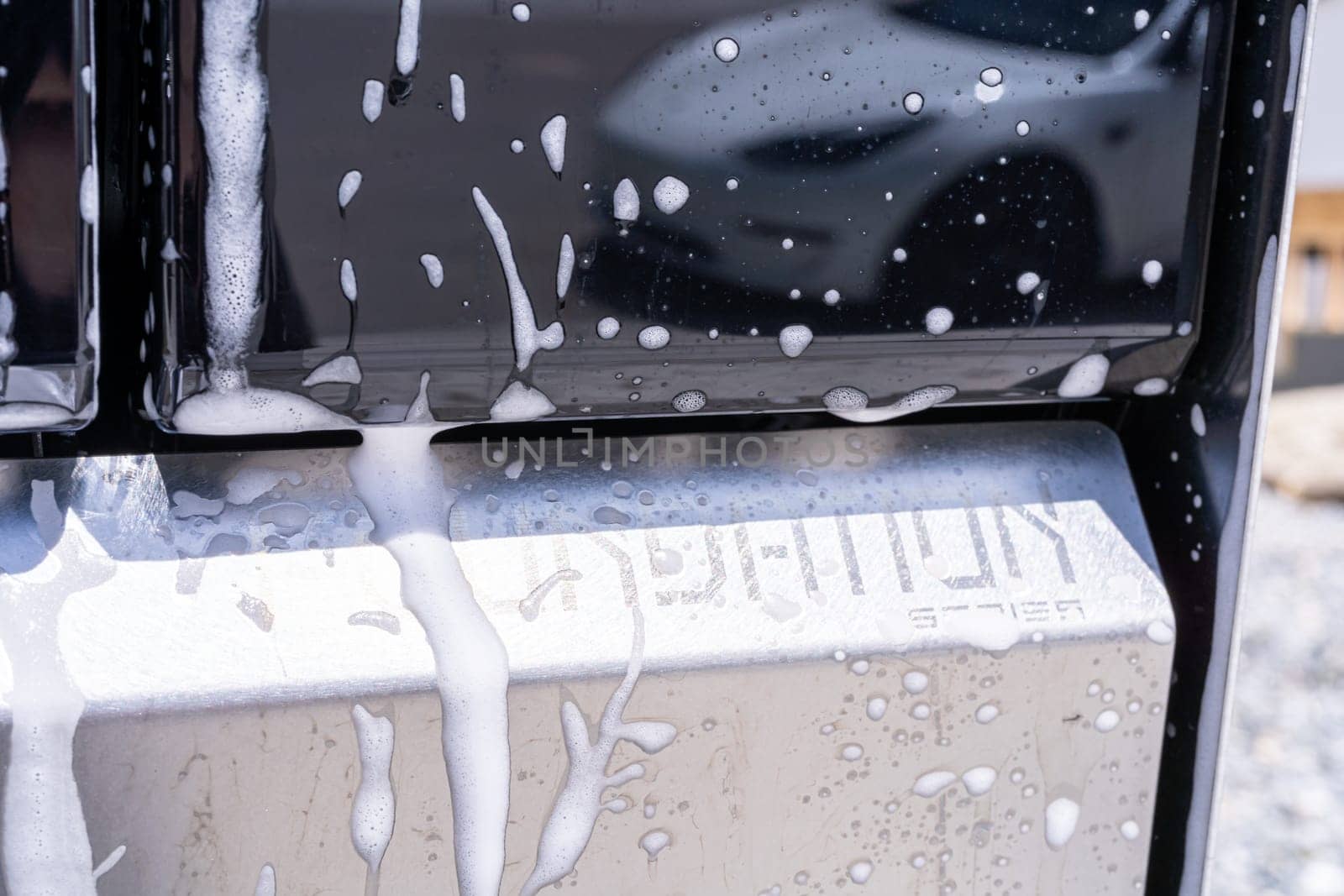 Denver, Colorado, USA-May 5, 2024-This image captures soapy water streaming beautifully down the metallic, angular side of a Tesla Cybertruck during a wash. The close-up showcases the sleek lines and unique design of the vehicle.