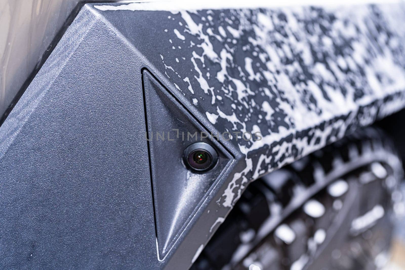 Denver, Colorado, USA-May 5, 2024-This image captures a close-up view of a side camera on the Tesla Cybertruck, covered in soap suds during a cleaning session, emphasizing the vehicle sleek design and modern features.