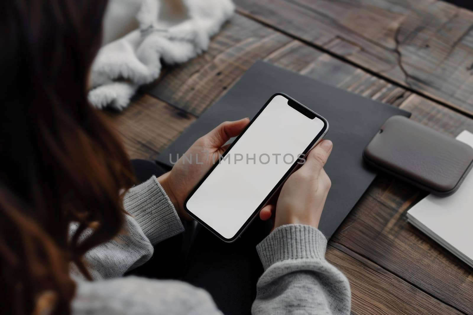 A woman holding a smartphone white screen on a wooden table by golfmerrymaker