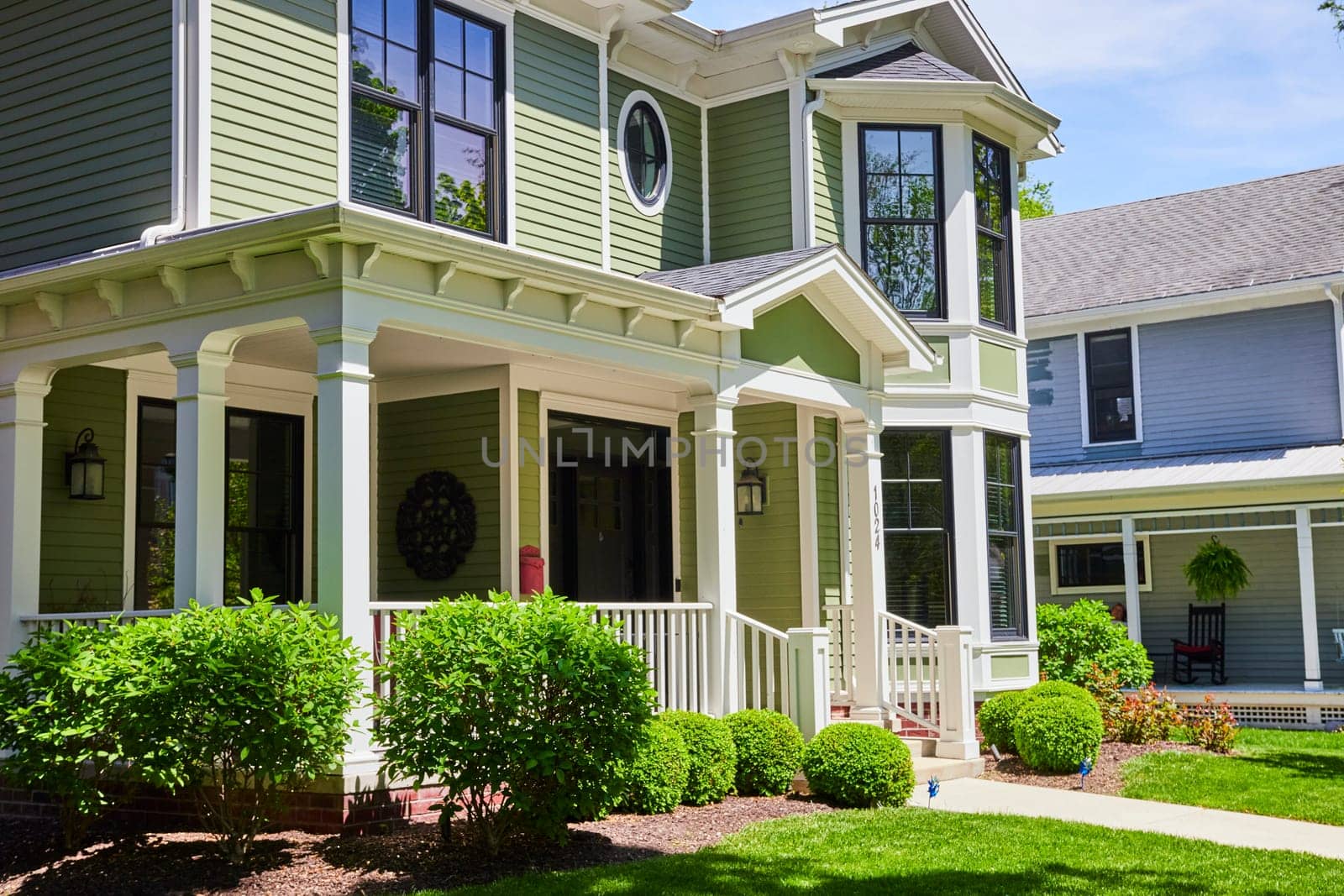 Charming sage green home in Fort Wayne's historic West Central neighborhood, showcasing elegant architecture and lush landscaping.