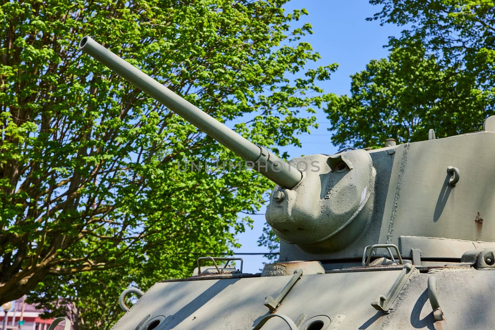 Aged military tank in Warsaw, Indiana, stands among lush greenery, symbolizing peace and history.