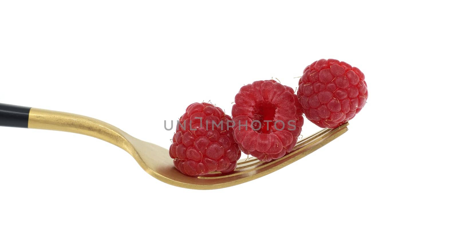 Red raspberries neatly stacked on the prongs of a gold fork with a black handle isolated on a white background, Healthy diet, organic food concept