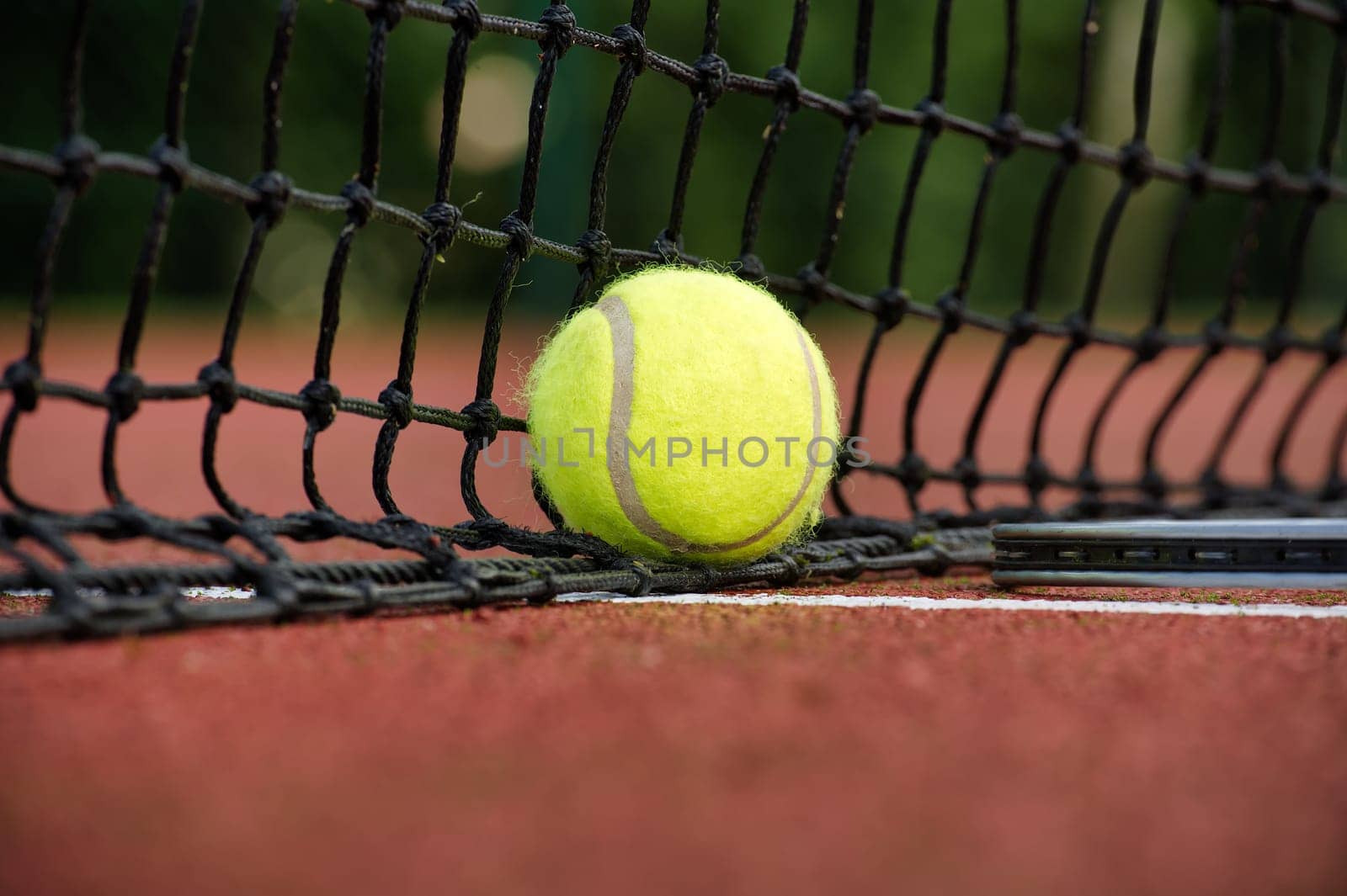 Tennis scene with black net, ball on white line in low angle view