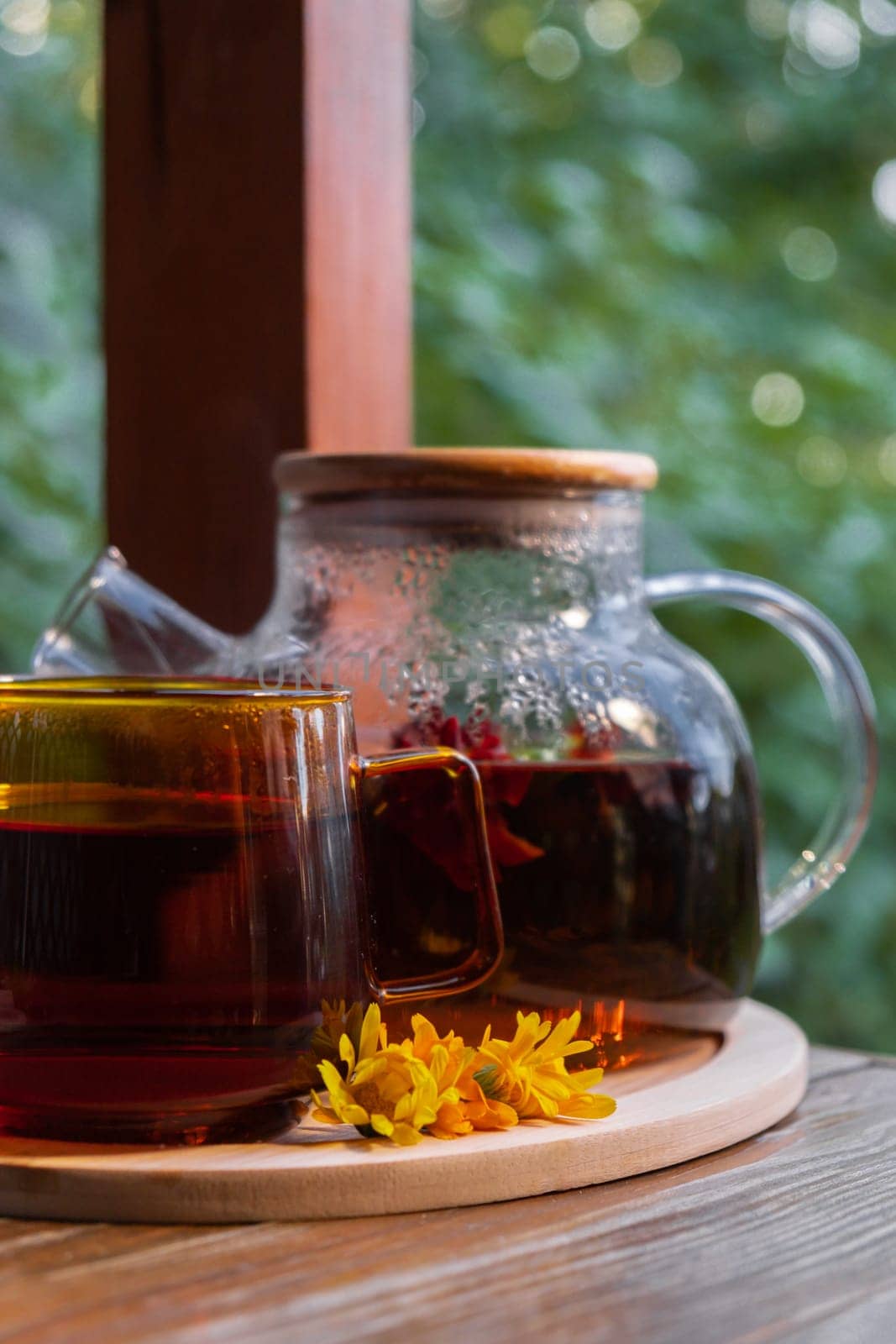 Calendula tea still life on table in green garden background. Healthy hot drink benefits. Natural organic aromatic drink in cup. Home-grown immunity-boosting herbs for tea. Autumn winter warming drink by anna_stasiia