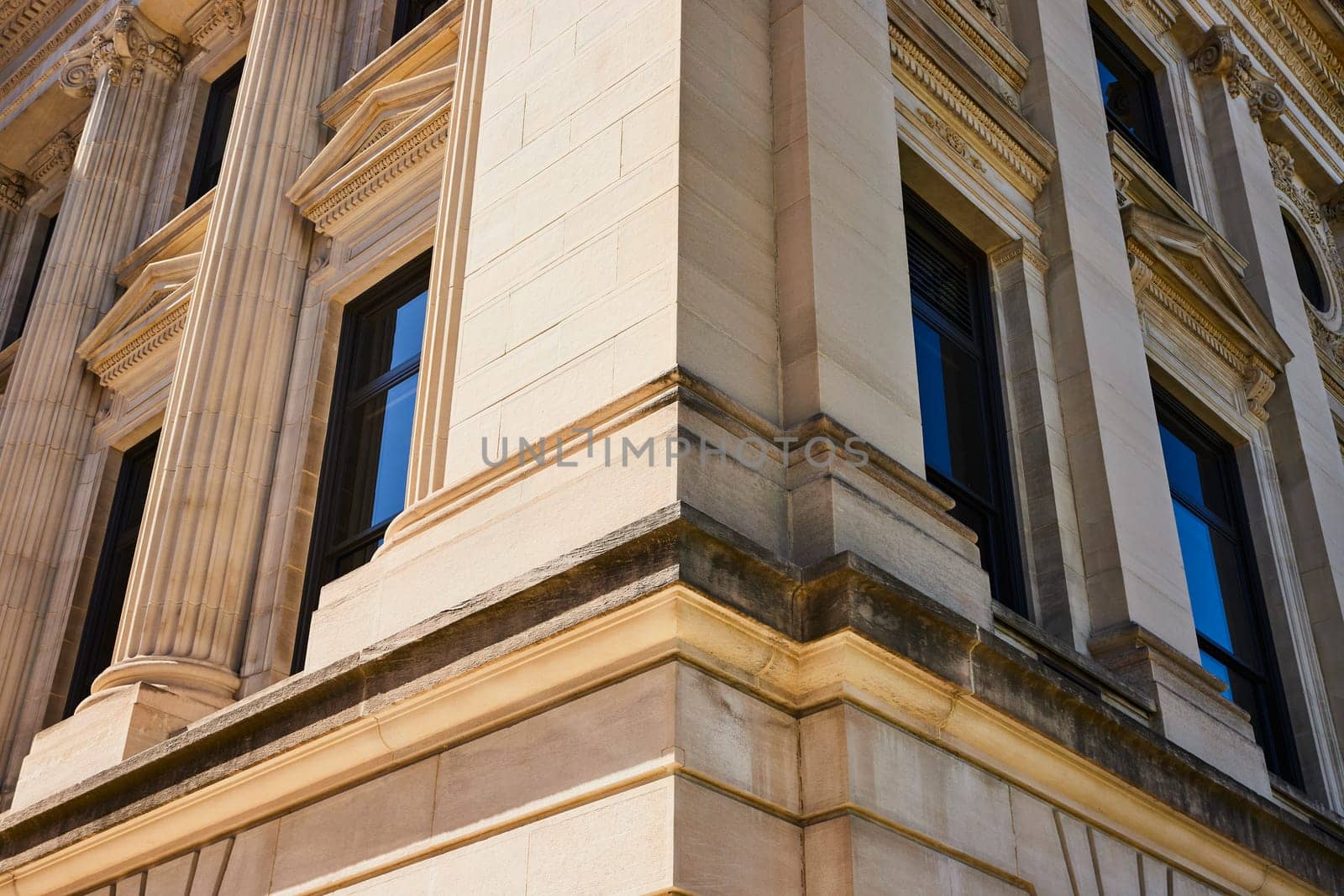 Classical yet modern architectural facade in downtown Fort Wayne, showcasing ornate columns and blue windows.