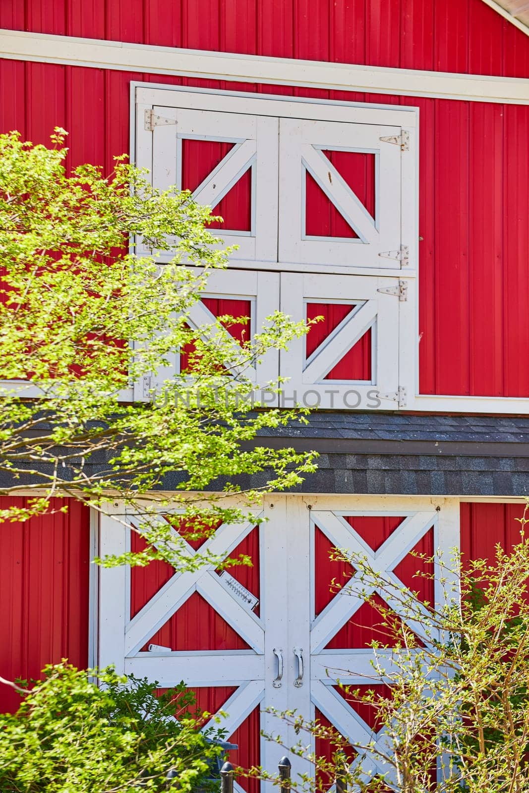 Vibrant red barn with white doors in a lush spring setting, Fort Wayne, Indiana. Perfect for rural and agricultural themes.