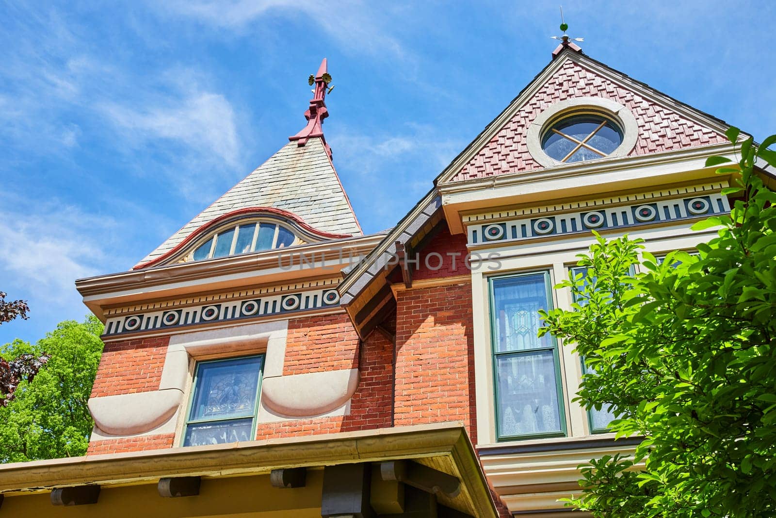 Victorian elegance in Fort Wayne: Historic home showcases ornate roofs and lush greenery against a blue sky.