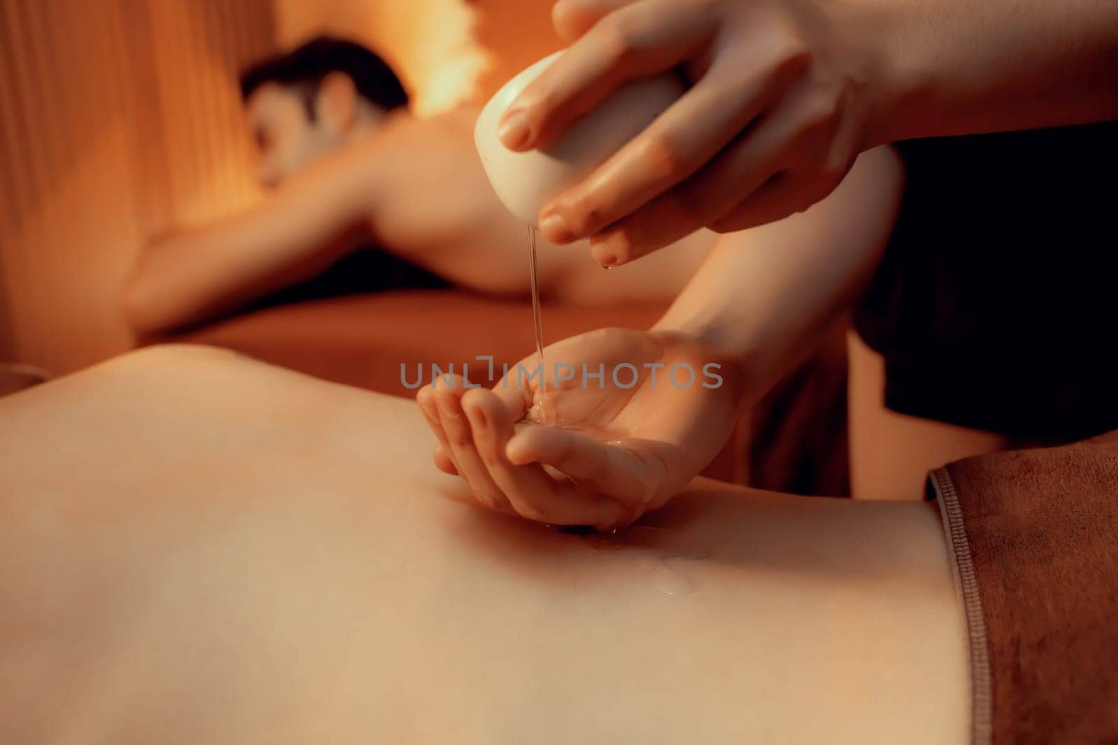 Masseur hands pouring aroma oil on couple customer back. Masseuse prepare oil massage procedure for customer at spa salon in luxury resort. Aroma oil body massage therapy concept. Quiescent