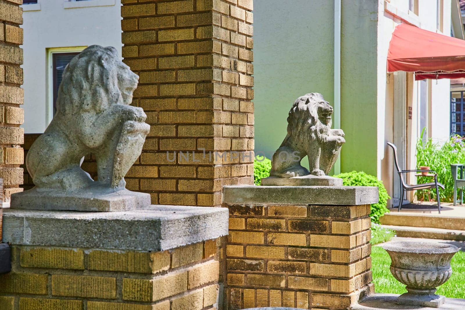 Elegant stone lions guard a historic home in Fort Wayne, symbolizing tradition and security under a clear blue sky.