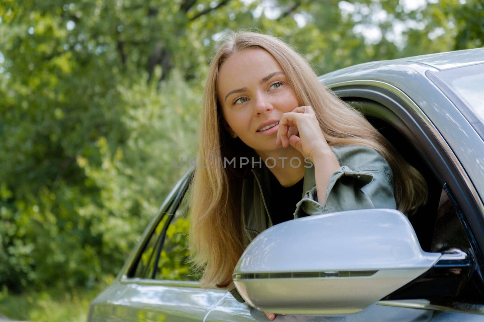 Blonde woman sticking head out of windshield car. Young tourist explore local travel making candid real moments. True emotions expressions of getting away and refresh on open clean air by anna_stasiia