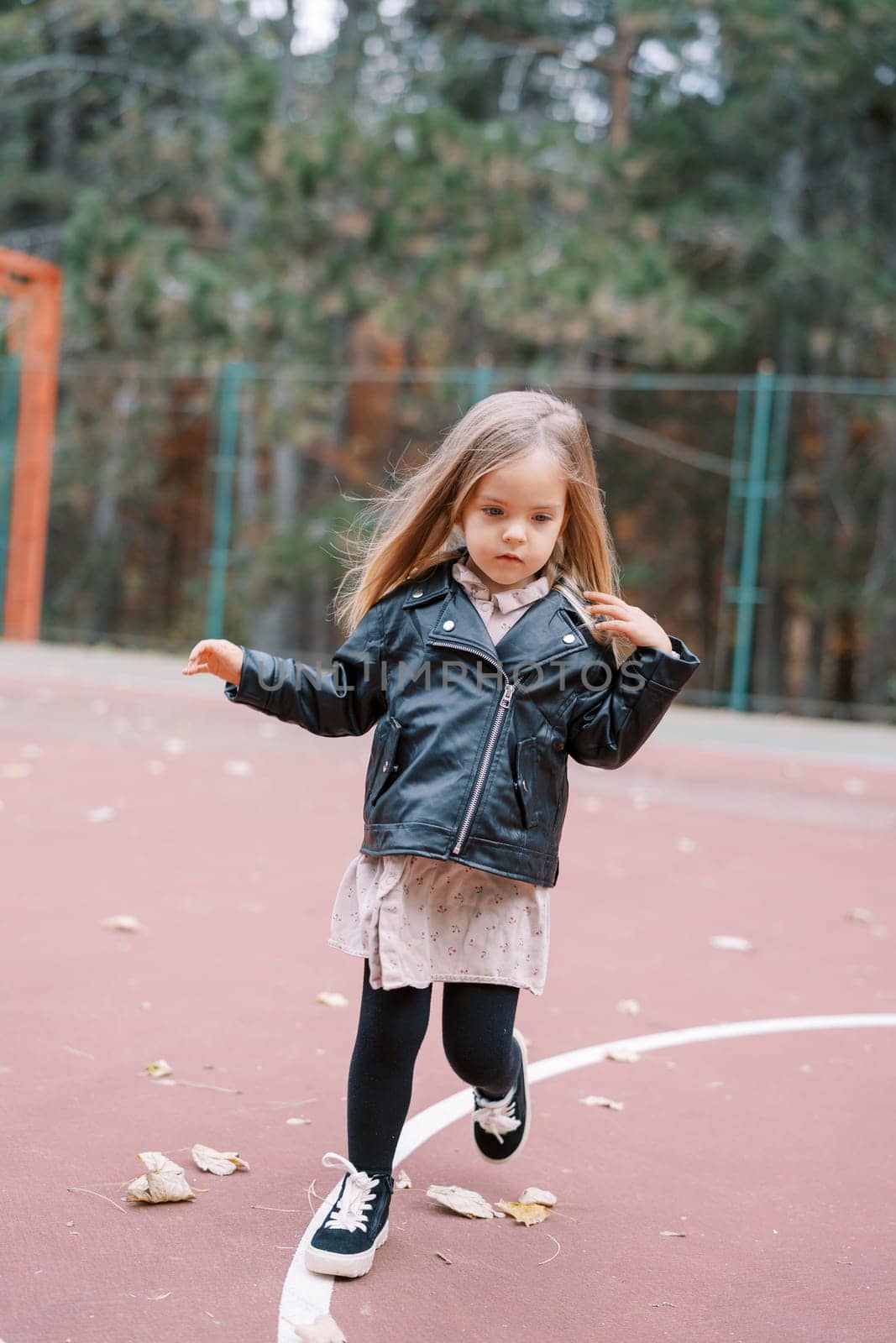 Little girl with flying hair walks on the playground. High quality photo