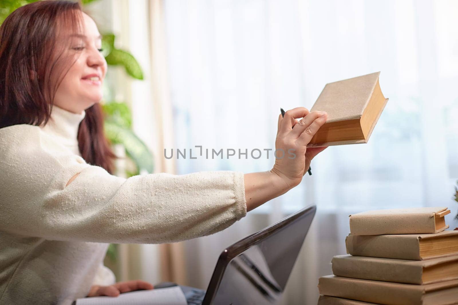 Middle aged reader Woman Enjoying a Book by a Window. Confidence Business woman in cozy room. Professional, psychologist, businesswoman, lawyer, poet