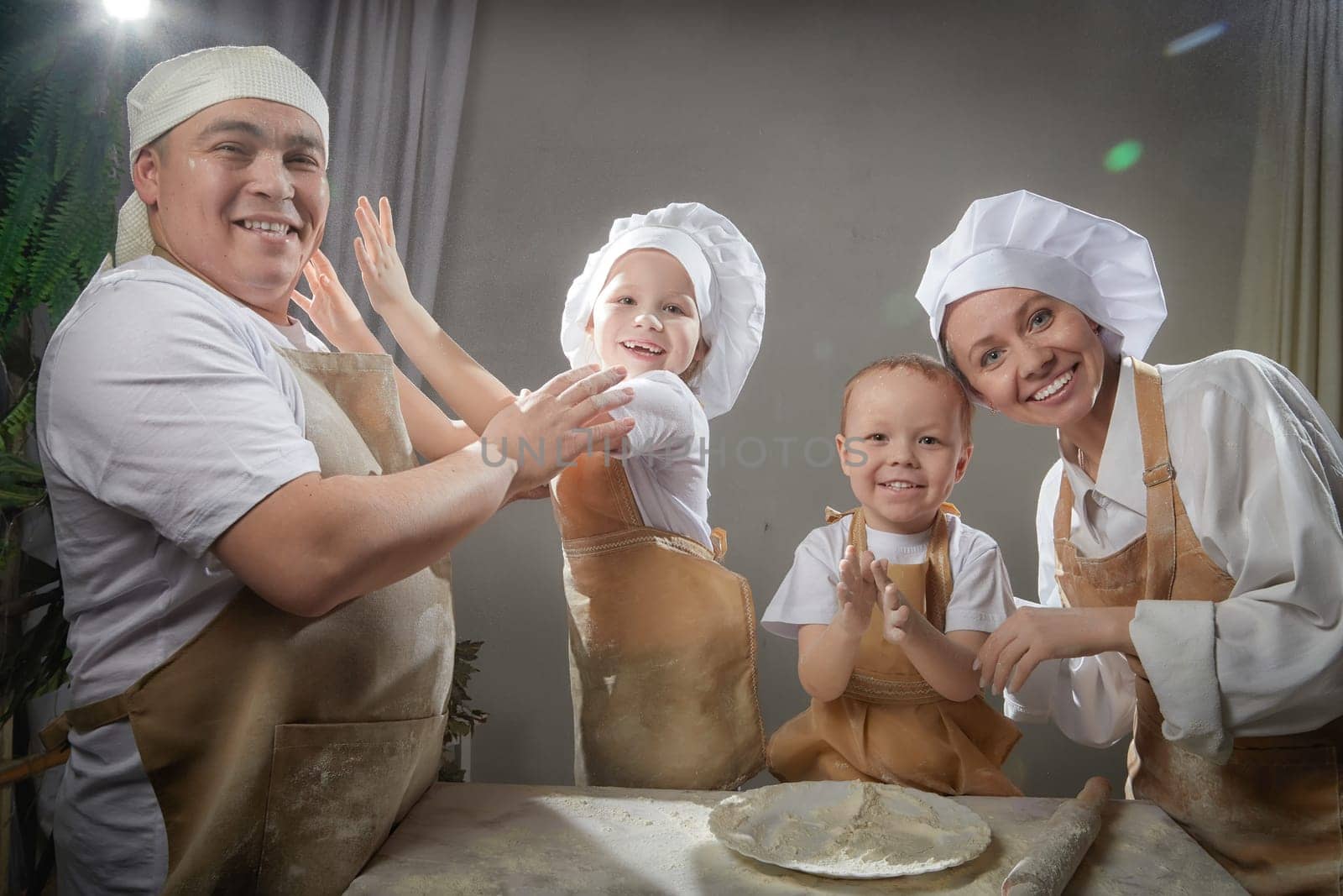 Cute oriental family with mother, father, daughter, son cooking in kitchen on Ramadan, Kurban-Bairam, Eid al-Adha. Funny family at photo shoot. Easter by keleny