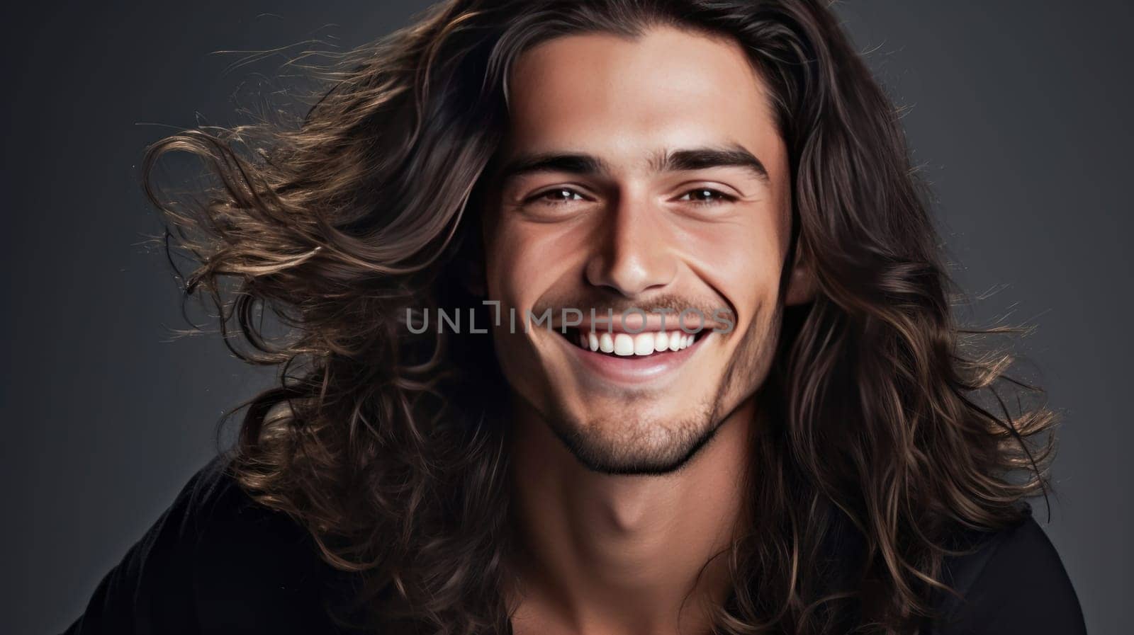 Portrait of an elegant sexy smiling Latino man with perfect skin and long hair, on a gray background. Advertising of cosmetic products, spa treatments shampoos and hair care products, dentistry and medicine, perfumes and cosmetology for men