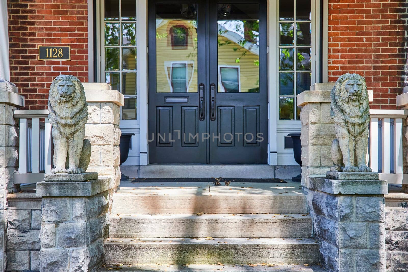 Elegant Fort Wayne home entrance with lion statues and lush greenery, symbolizing security and luxury.