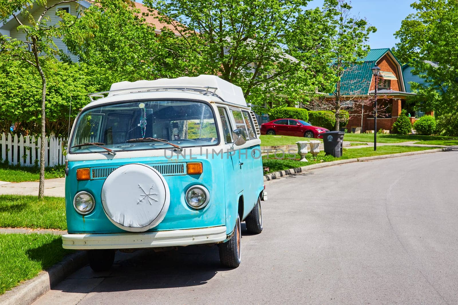 Vintage light blue Volkswagen van parked in a sunny, suburban street in Fort Wayne, evoking nostalgia and freedom.