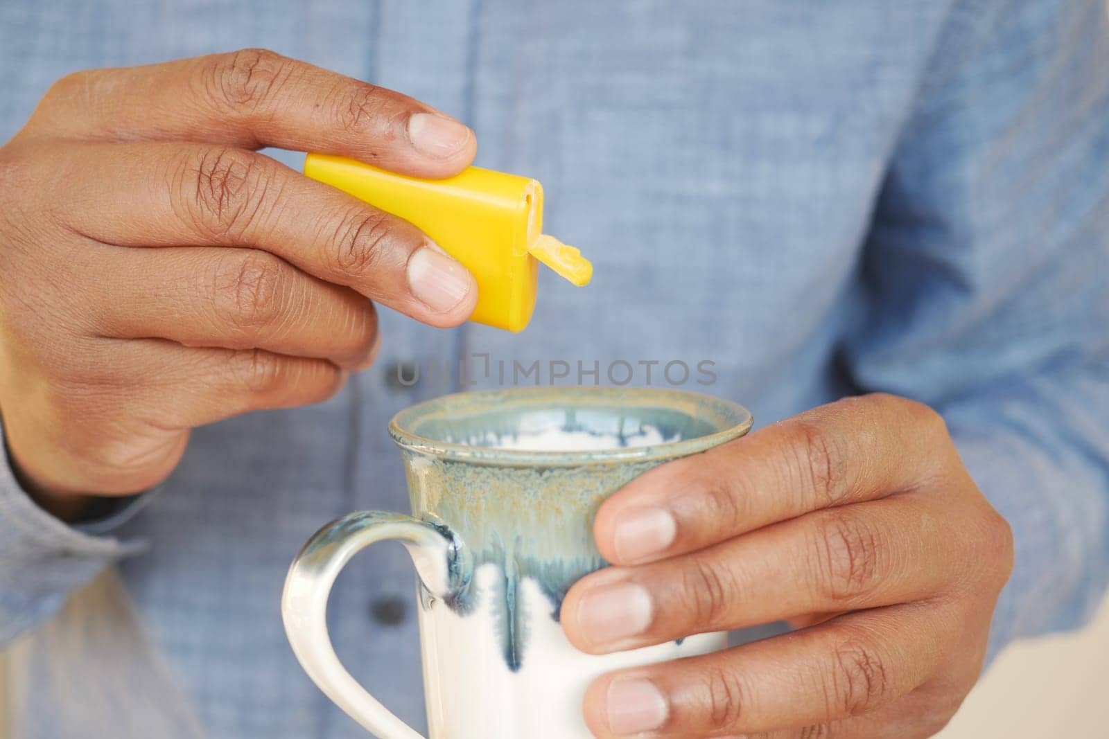 young man putting artificial sweetener in tea