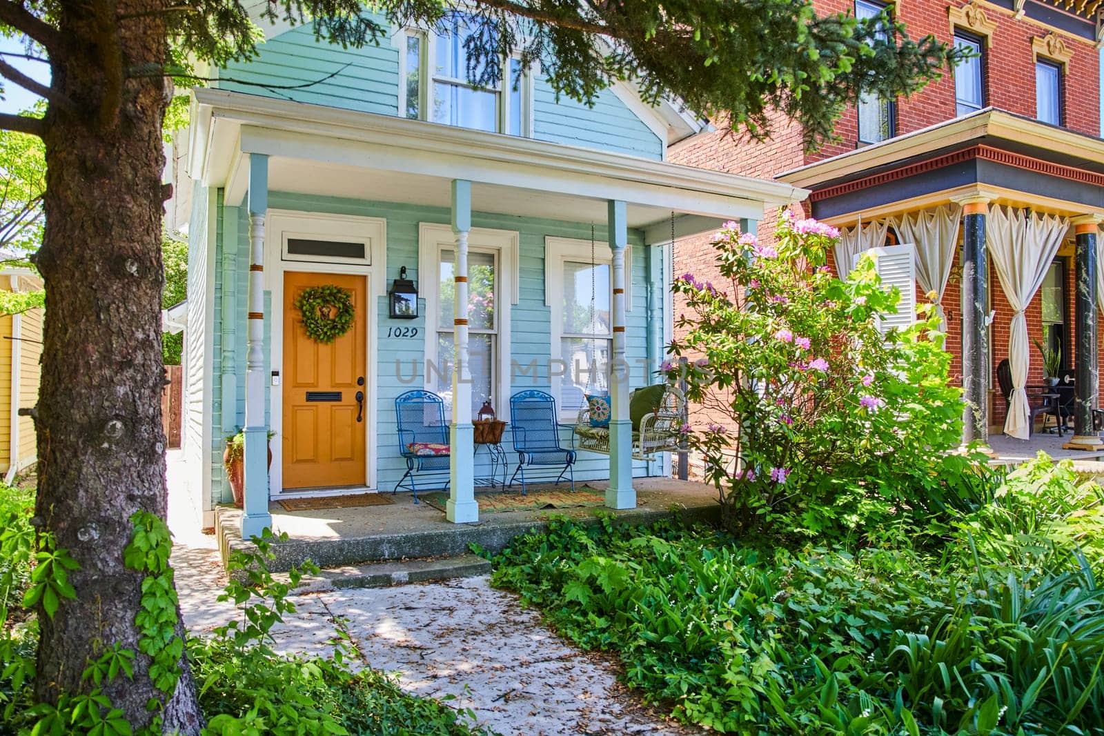 Cozy American home in Fort Wayne with bright orange door and lush greenery, perfect for suburban living.