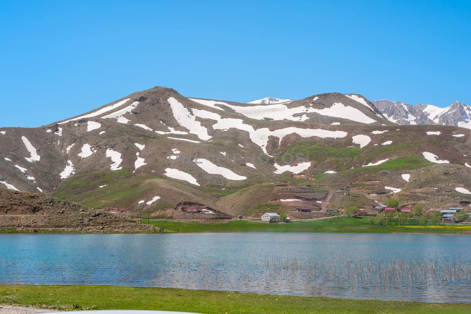 The lush green Sobucimen plateau in spring and the mountains with some melted snow behind.