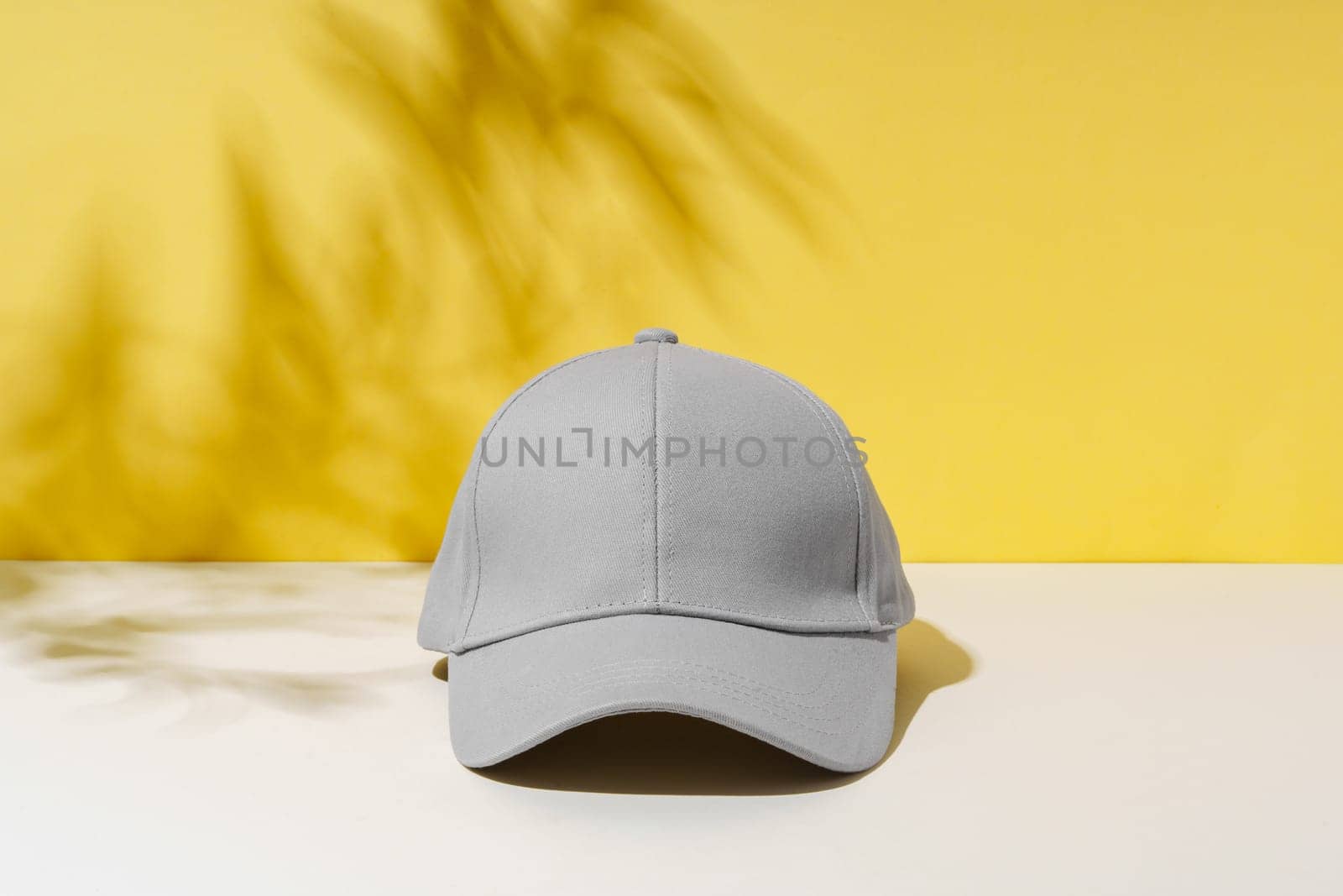 Baseball hat against yellow background in studio by Fabrikasimf