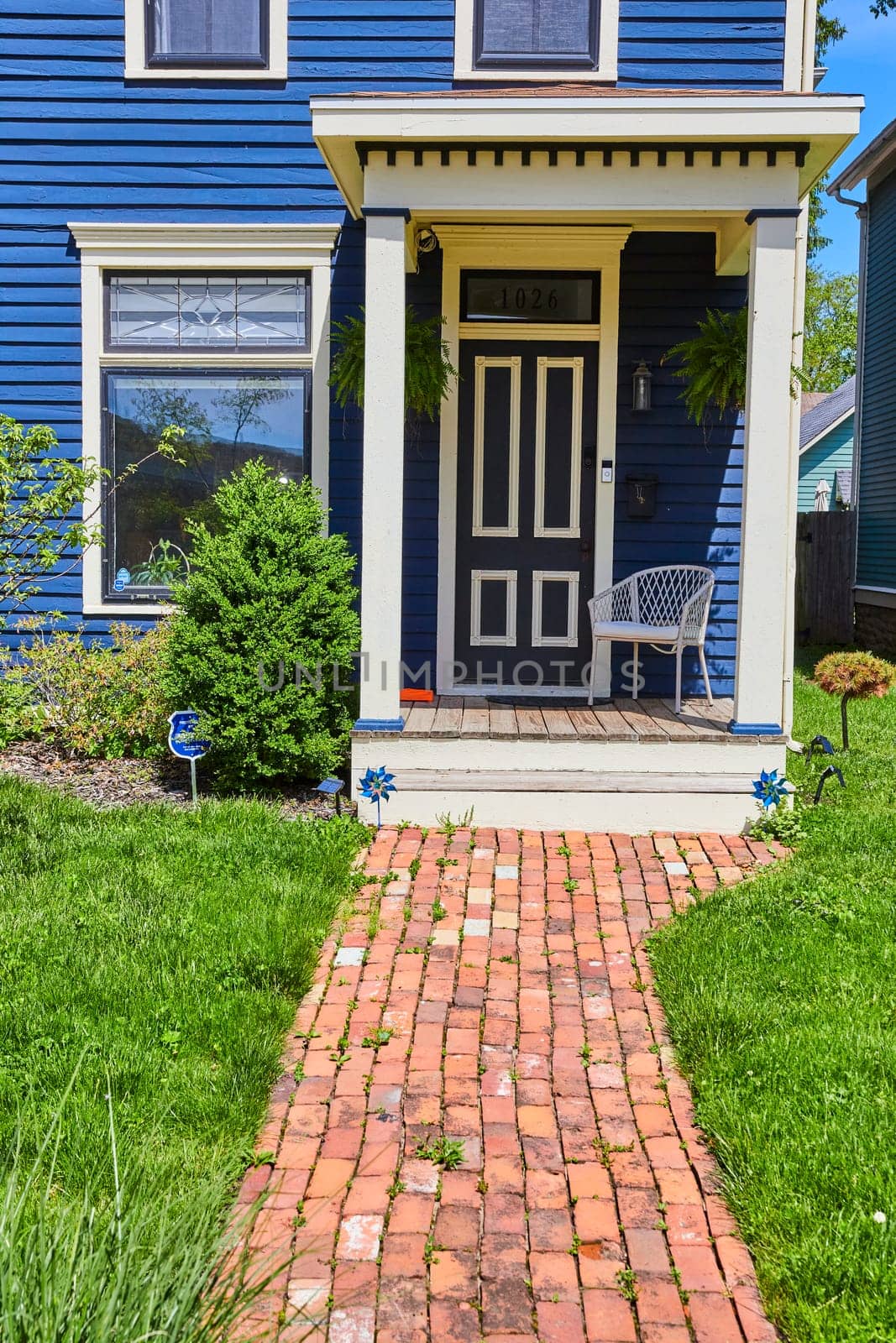 Charming navy blue home with white trim and cozy porch in sunny Fort Wayne, perfect for a welcoming feel.