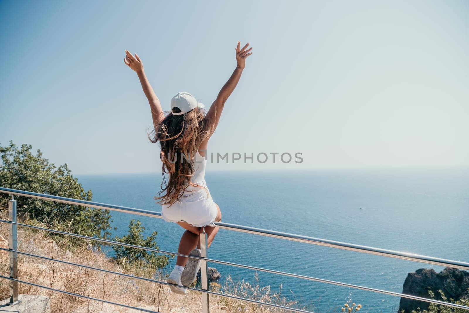 Woman travel sea. Young Happy woman in a long red dress posing on a beach near the sea on background of volcanic rocks, like in Iceland, sharing travel adventure journey