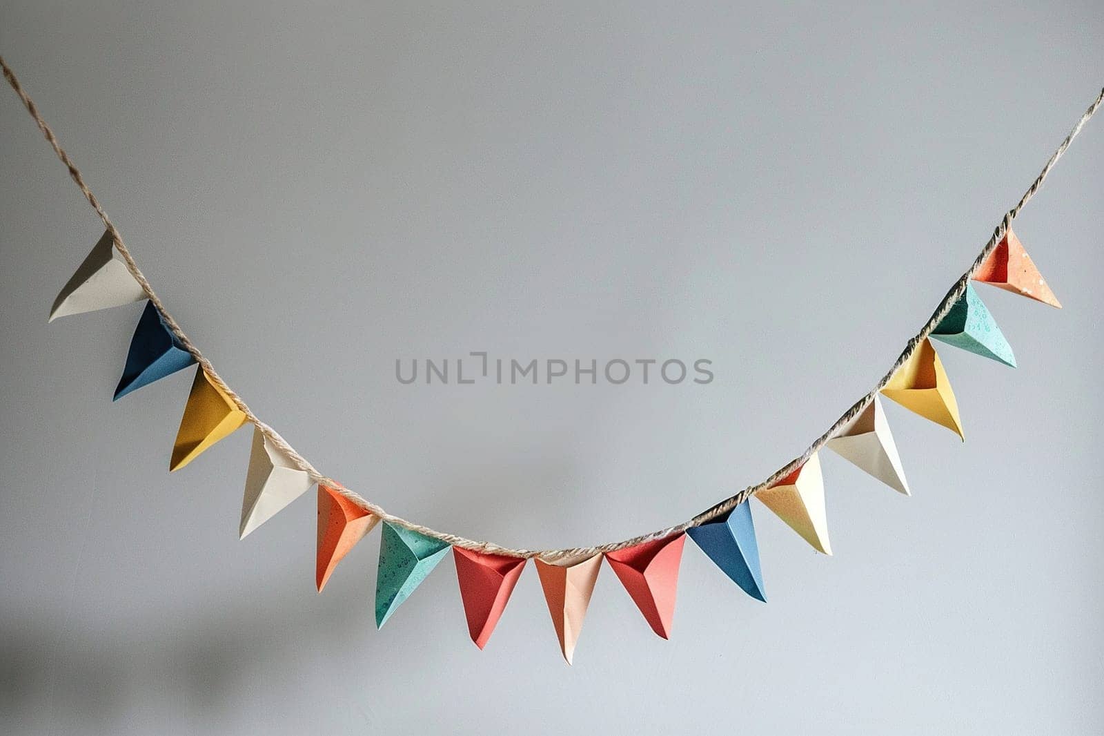 Colorful holiday flags in the form of a garland on the wall. The garland hangs in one row. Congratulatory background with place for text.