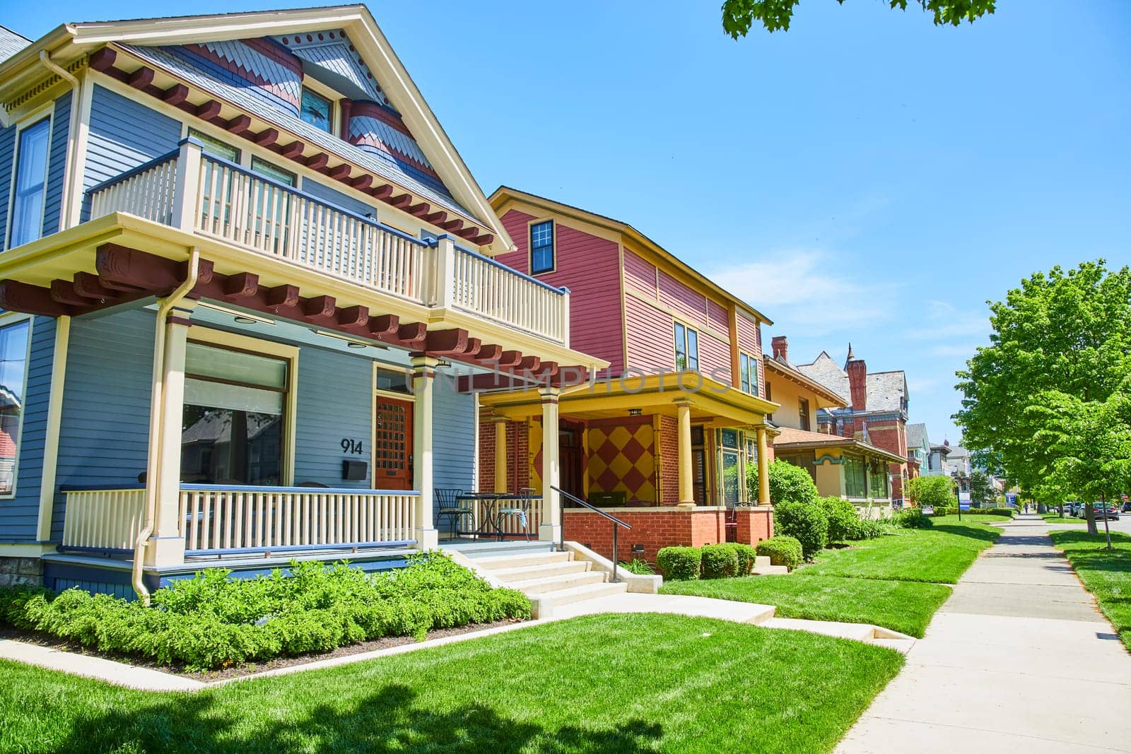 Colorful Victorian homes line a lush, inviting street in Fort Wayne, showcasing community charm and architectural beauty.